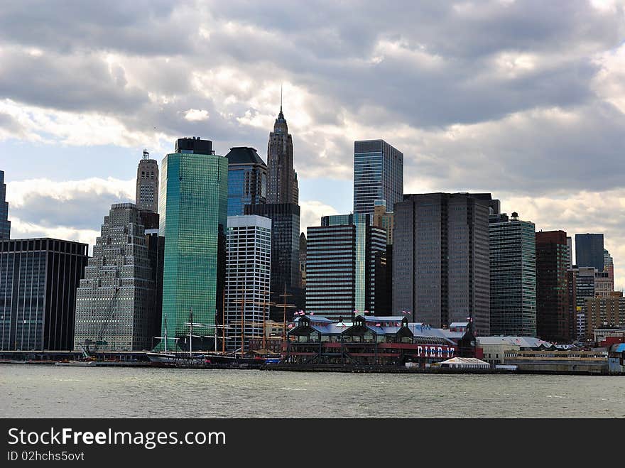 Lower Manhattan Skyline from Brooklyn under a cloudy sky.