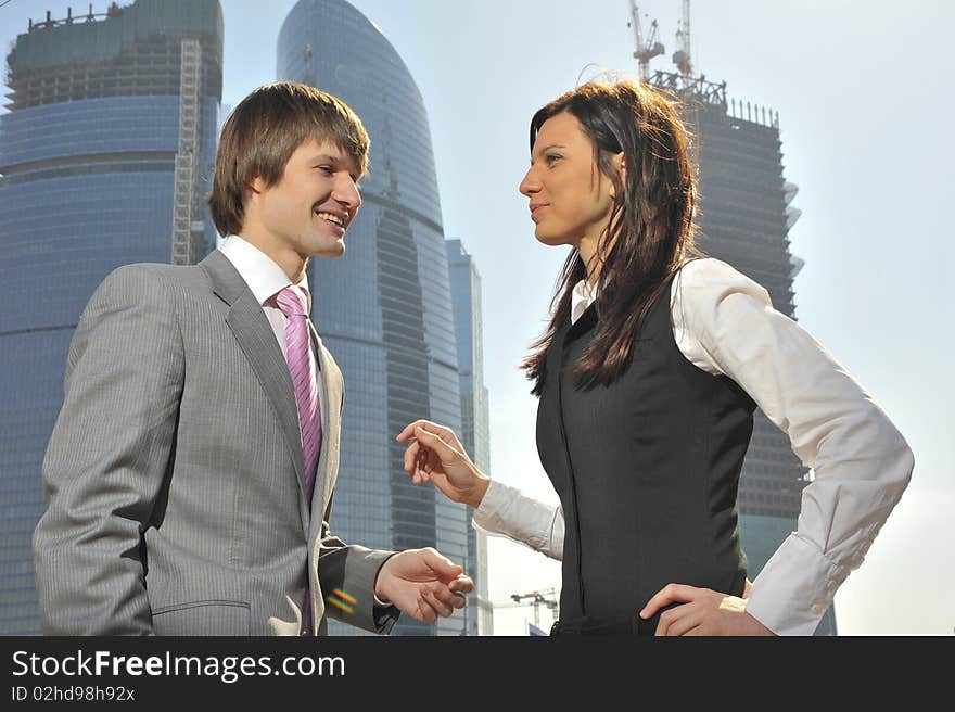 Two businessmen discuss the project against a skyscraper