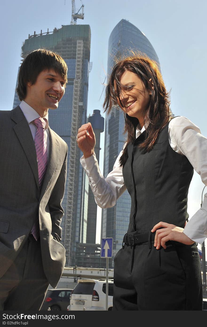 Two businessmen discuss the project against a skyscraper