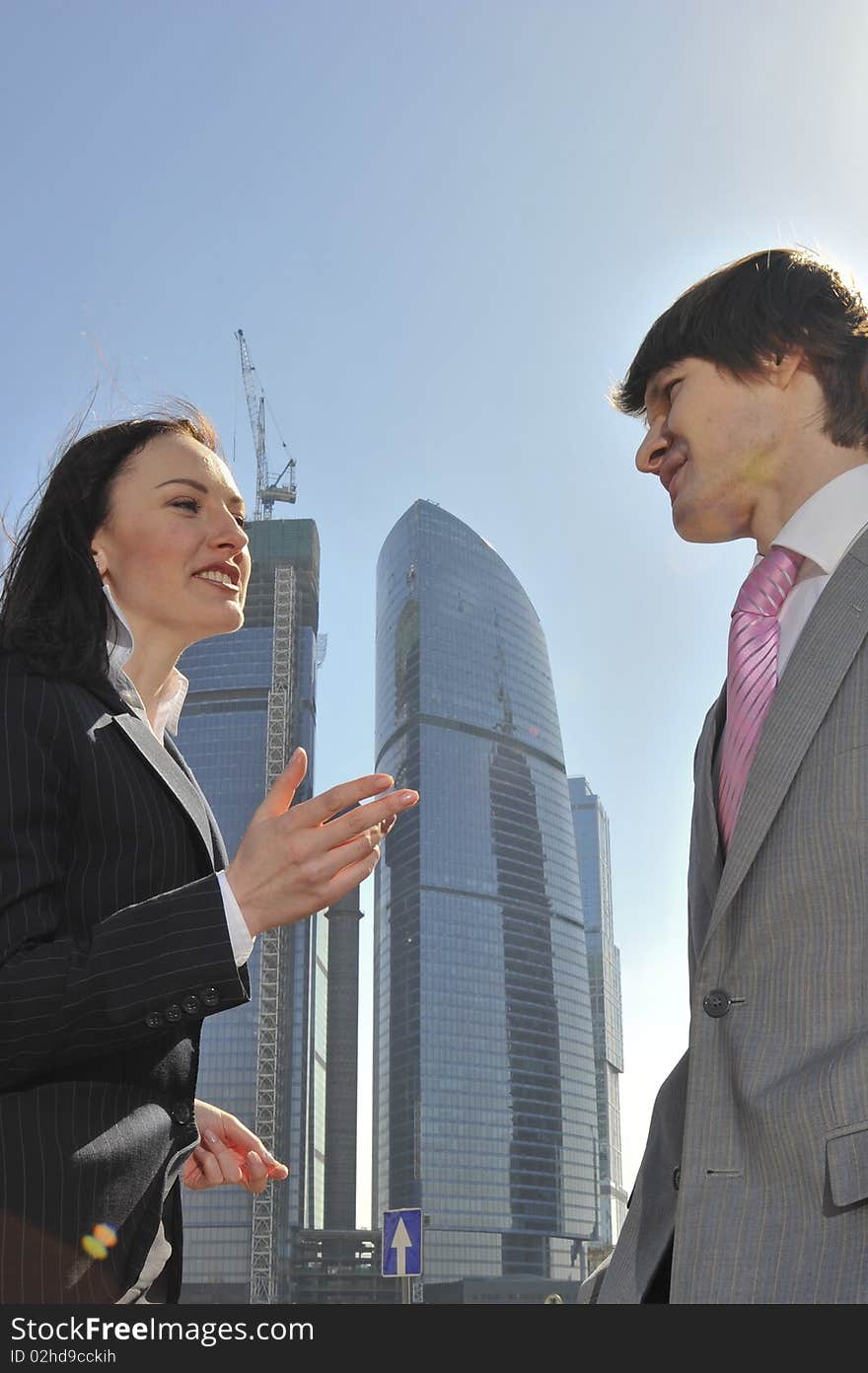 Two businessmen discuss the project against a skyscraper