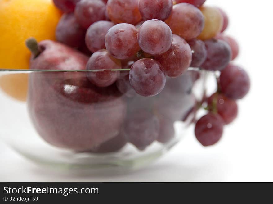 Pear, orange and grapes of red colour in a glass vase. Pear, orange and grapes of red colour in a glass vase