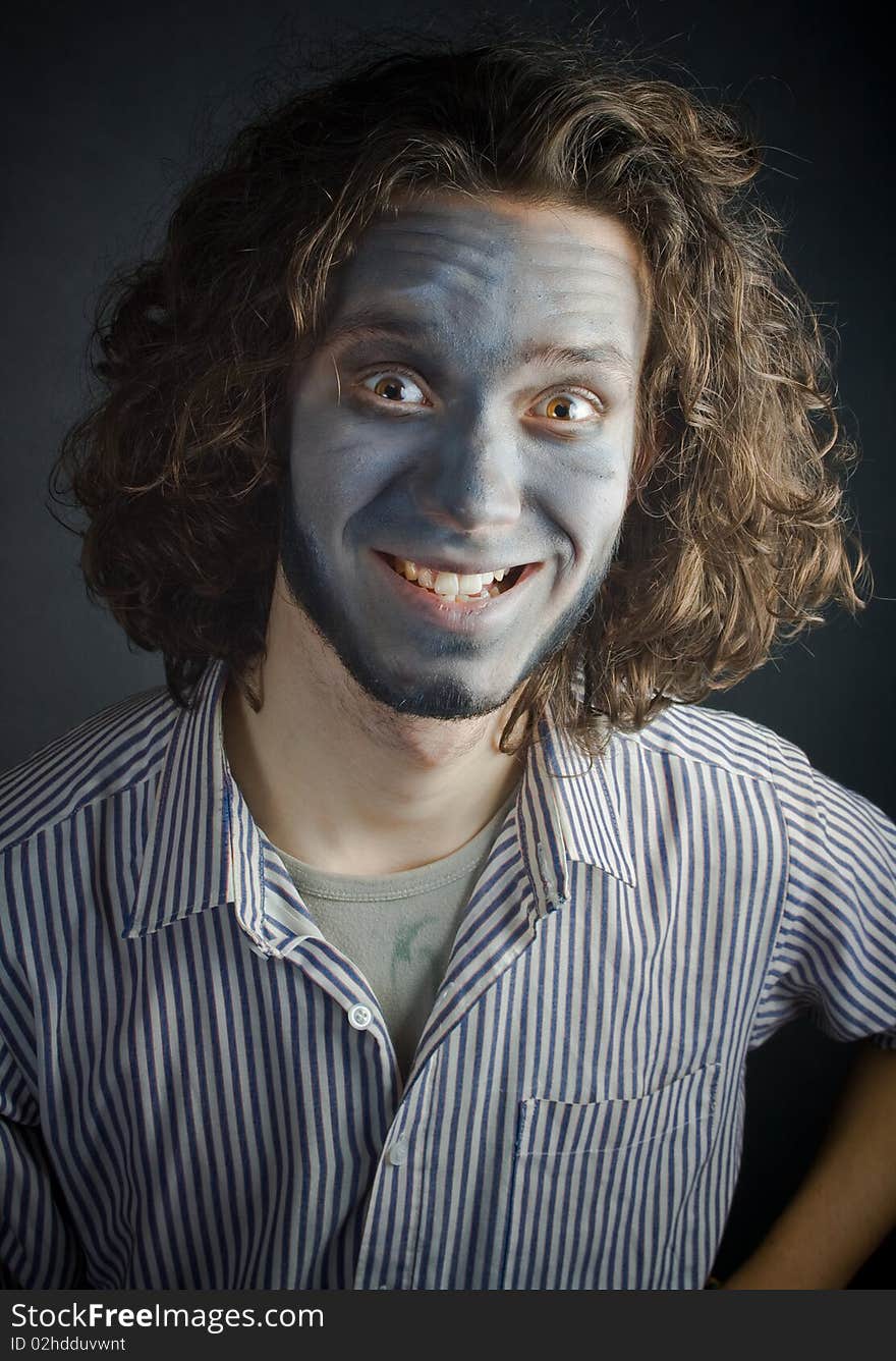 Smiling young man in make-up, with long hair, on a black background