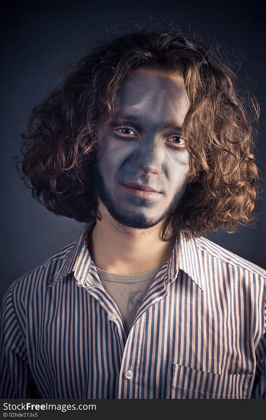 Young man in make-up with long hair on a black background