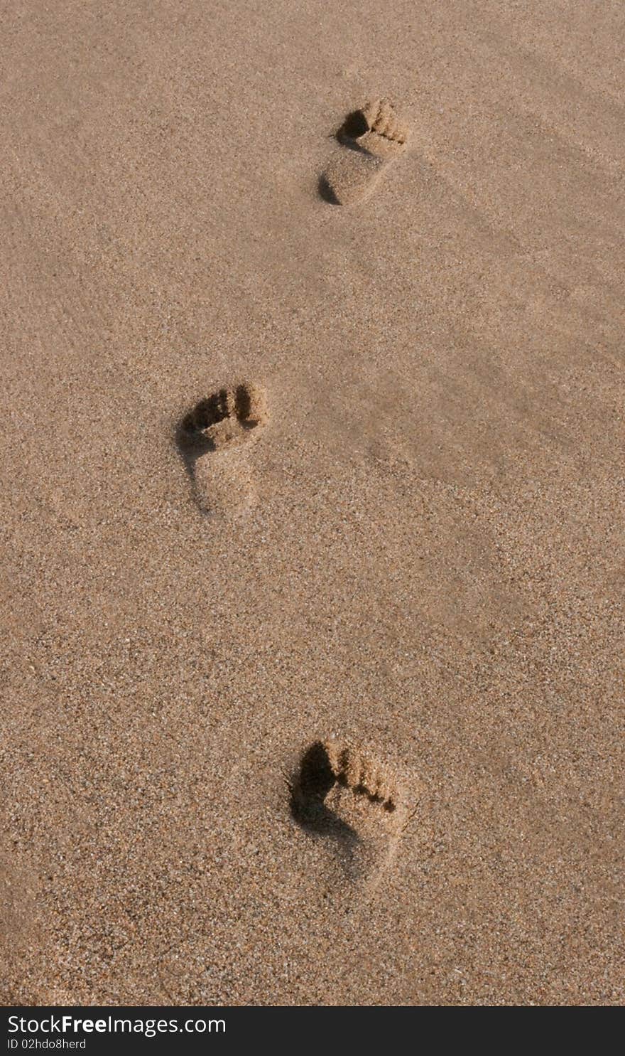 Three footprints on the beach sand