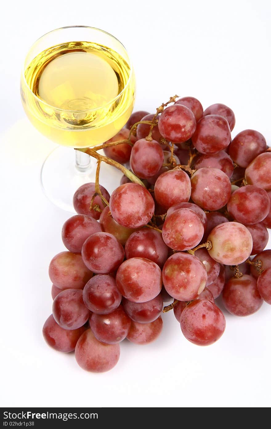 Glass of white wine and red grapes on white background. Glass of white wine and red grapes on white background