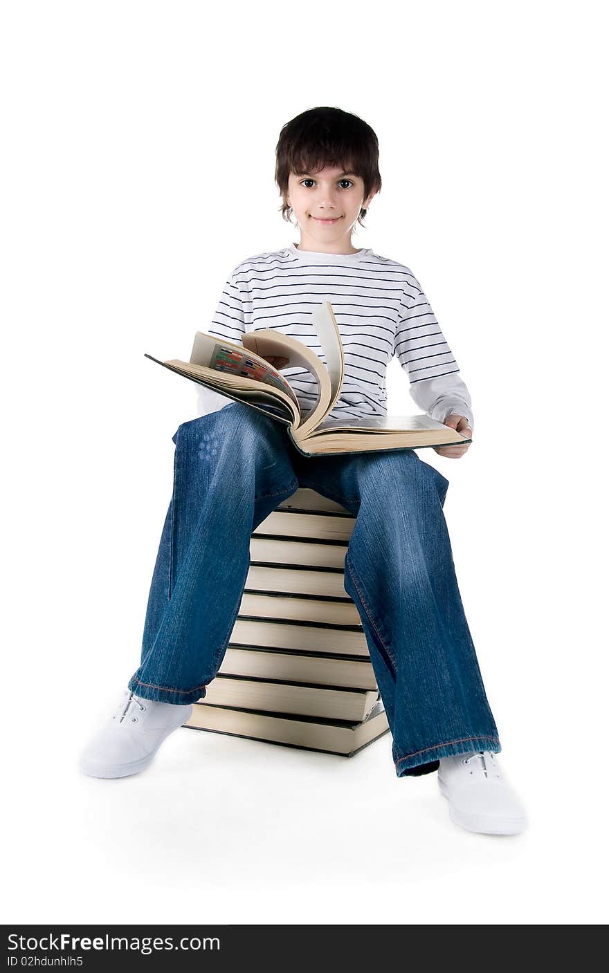 Cute little boy sit on a stack of big books on white background