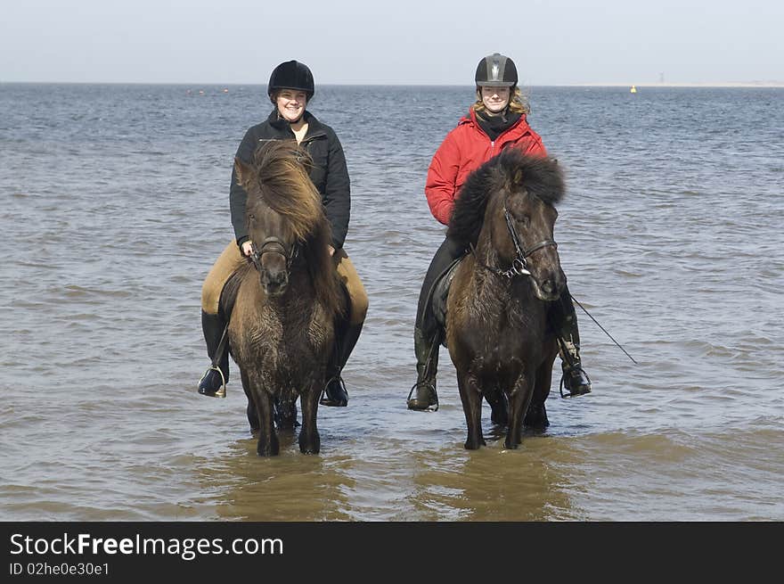 Two amazones on horseback on the beach