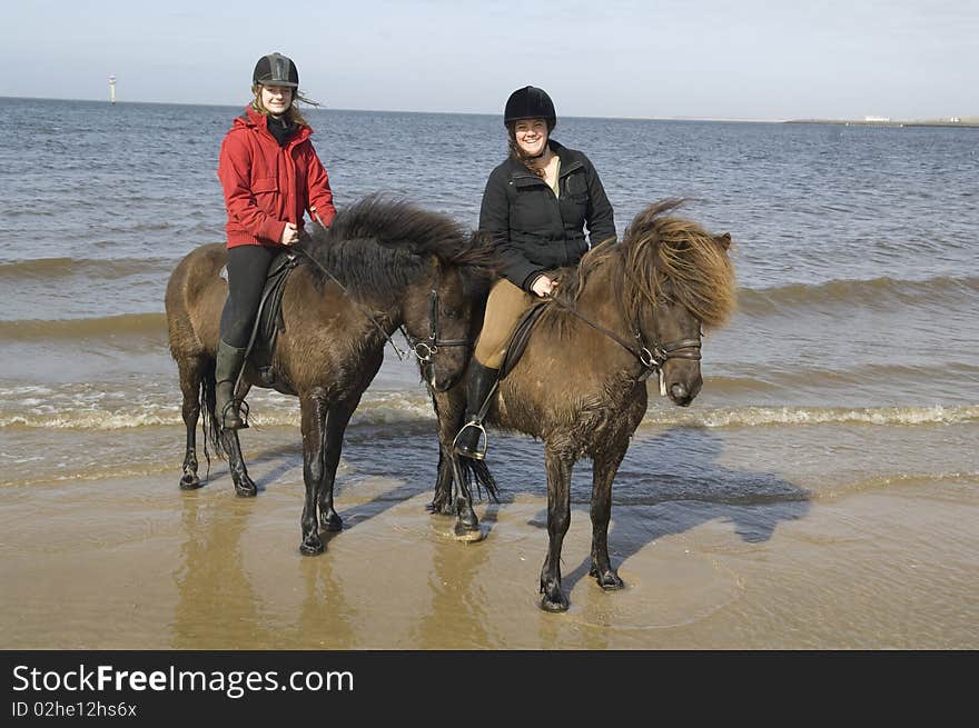 Two amazones on horseback on the beach