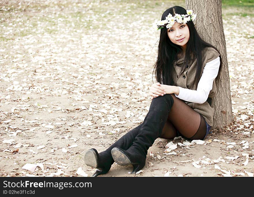 Asian smile girl sitting under the tree in spring. Asian smile girl sitting under the tree in spring.