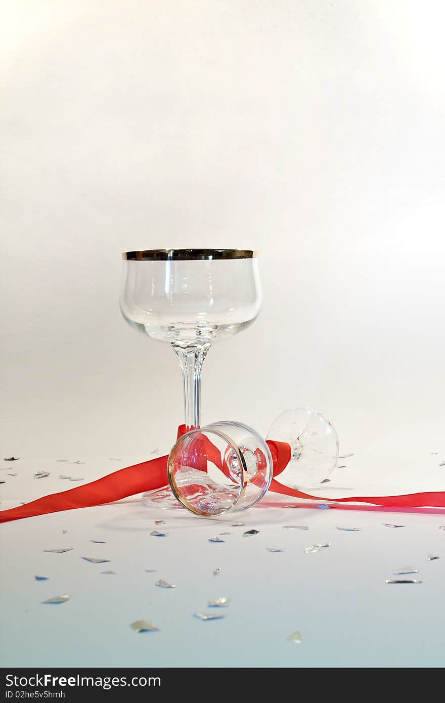 Picture of two glasses with gold edge  on a party table with red ribbon and silver chads. Picture of two glasses with gold edge  on a party table with red ribbon and silver chads