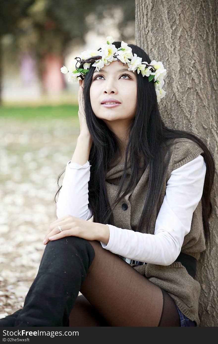 Beautiful Asian girl sitting under the tree,she is enjoying spring's scenery . Beautiful Asian girl sitting under the tree,she is enjoying spring's scenery .