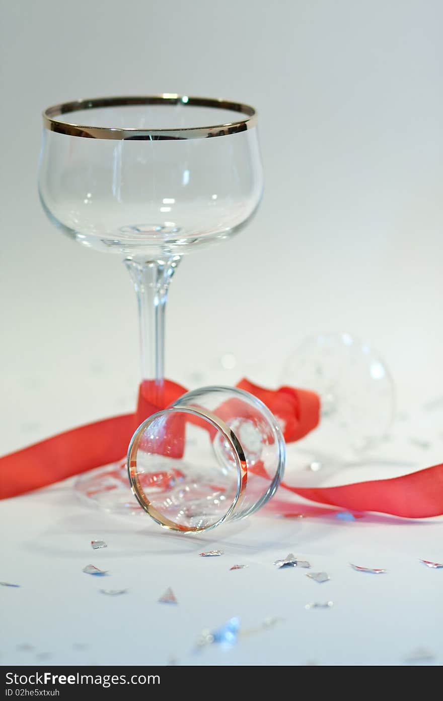 Picture of two glasses with gold edge  on a party table with red ribbon and silver chads. Picture of two glasses with gold edge  on a party table with red ribbon and silver chads