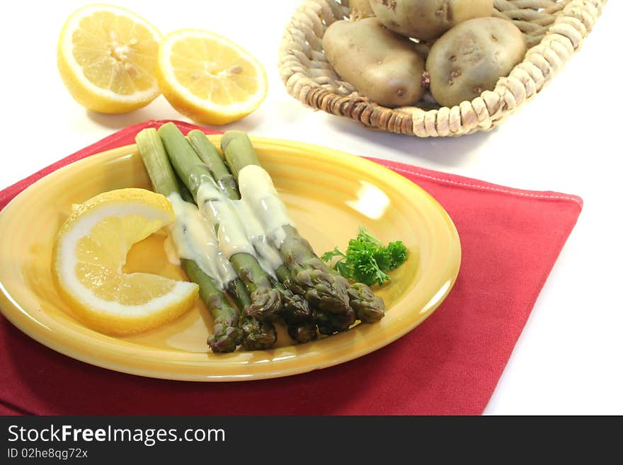 A bundle of green asparagus with lemon hollandaise sauce on a white background. A bundle of green asparagus with lemon hollandaise sauce on a white background