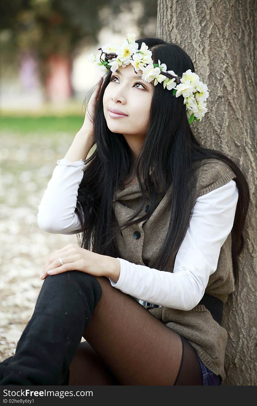 Asian smile girl sitting under the tree in spring.she is enjoying the spring scenery. Asian smile girl sitting under the tree in spring.she is enjoying the spring scenery.