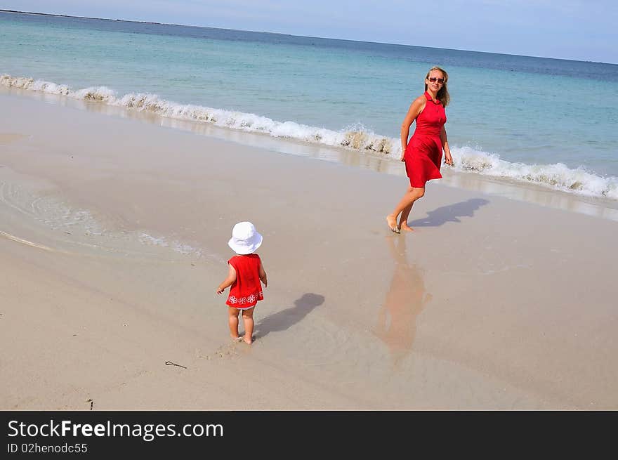 Mother and daughter walking along the ocean