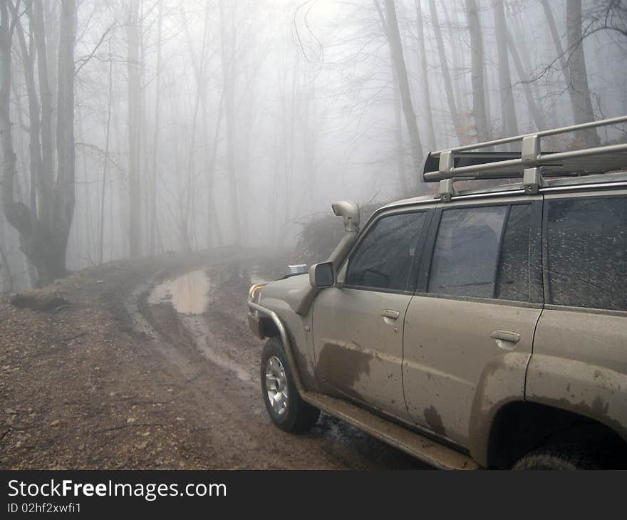 Dirty road and 4x4 car in autumn mist forest. Dirty road and 4x4 car in autumn mist forest