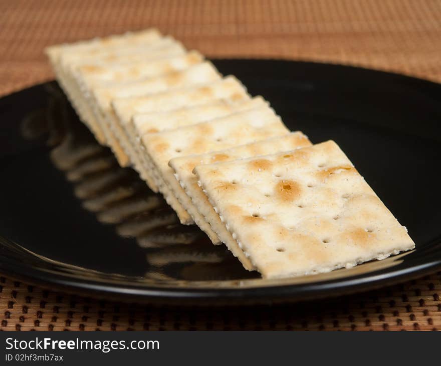 Row of Saltine Crackers on a black plate.