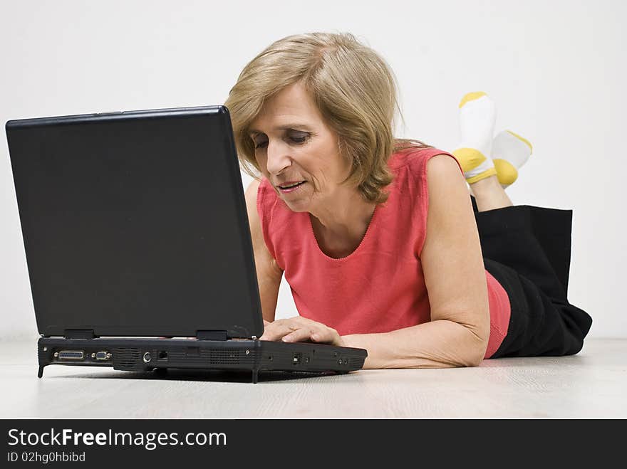 Senior woman relaxing  on floor and browsing internet on laptop,see more in <a href=http://www.dreamstime.com/people-on-couch-or-wooden-floor-rcollection11965-resi828293>People on couch or wooden floor</a>. Senior woman relaxing  on floor and browsing internet on laptop,see more in <a href=http://www.dreamstime.com/people-on-couch-or-wooden-floor-rcollection11965-resi828293>People on couch or wooden floor</a>