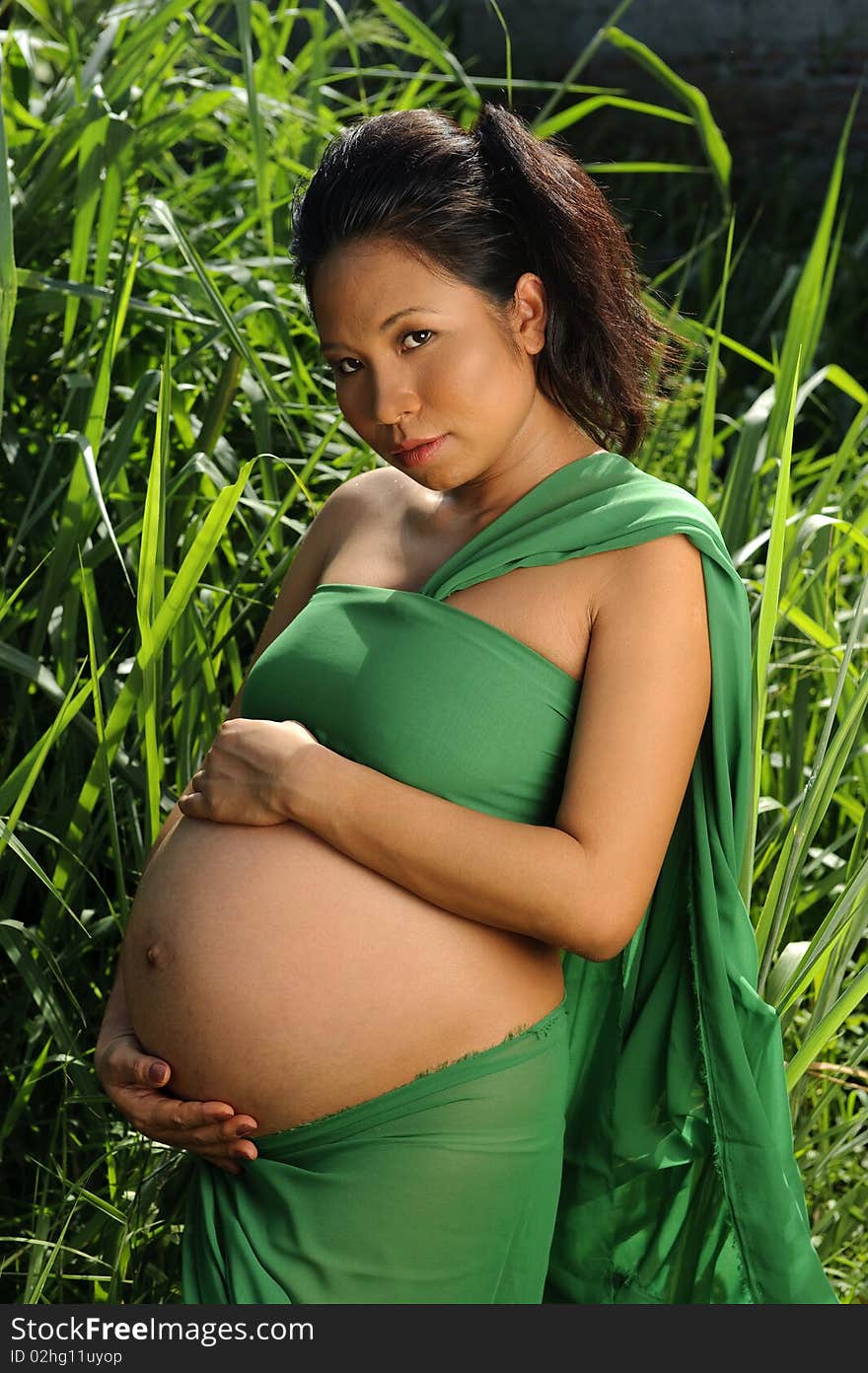 Woman poses with her unborn child outdoors. Woman poses with her unborn child outdoors