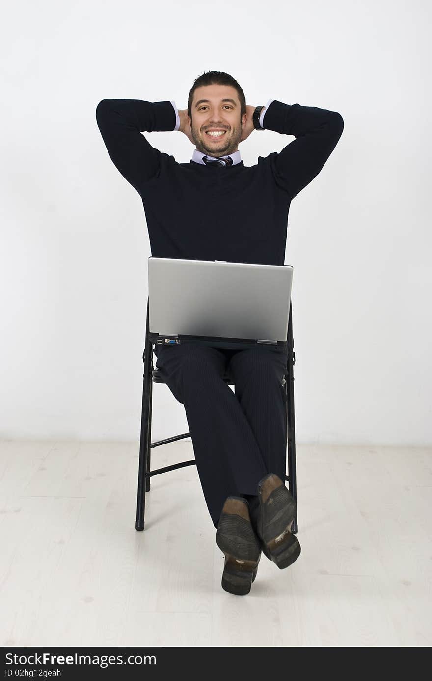 Happy businessman with laptop on chair