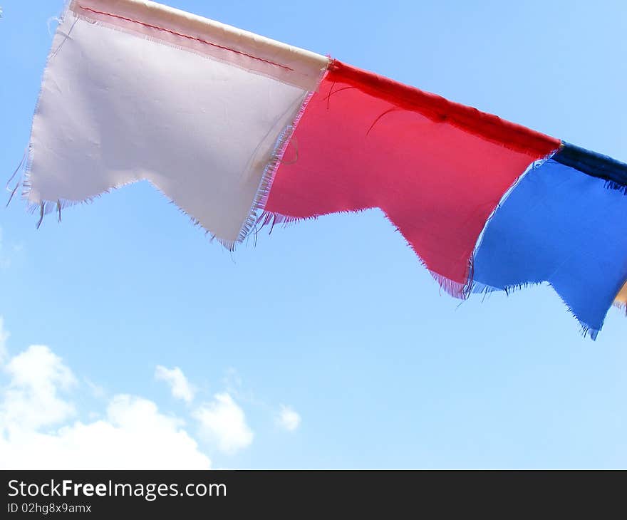 Three color flags on a wire and blue sky