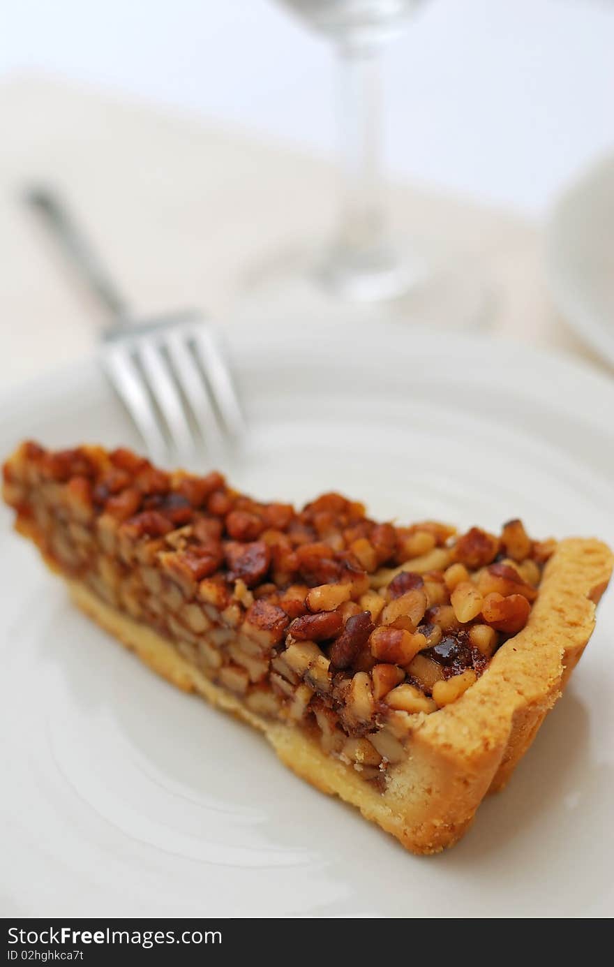 A single slice of hazel nut tart on white plate. For concepts such as food and beverage, diet and nutrition, and healthy eating.