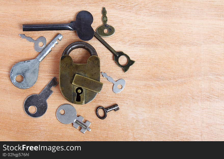 Old padlock and keys on wooden background