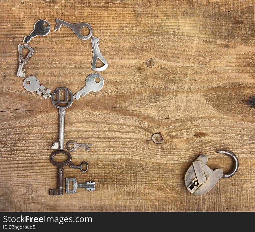 Old padlock and keys on wooden background