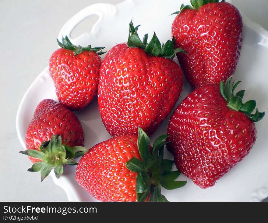 Close up view of some Strawberries on a white porcelain background