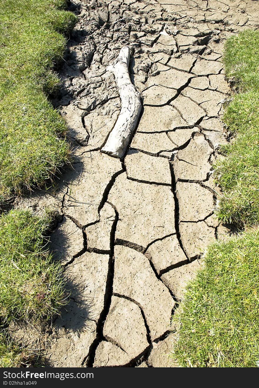A color landscape photo of a dried up riverbed with cracked mud and waffled patterns caused by global warming