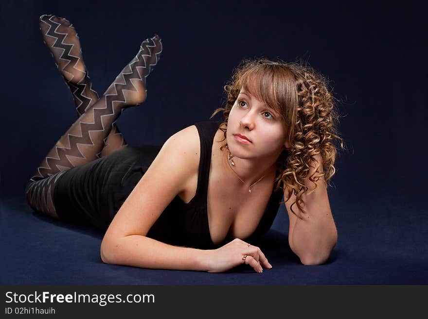 Glamorous young lying woman on black background