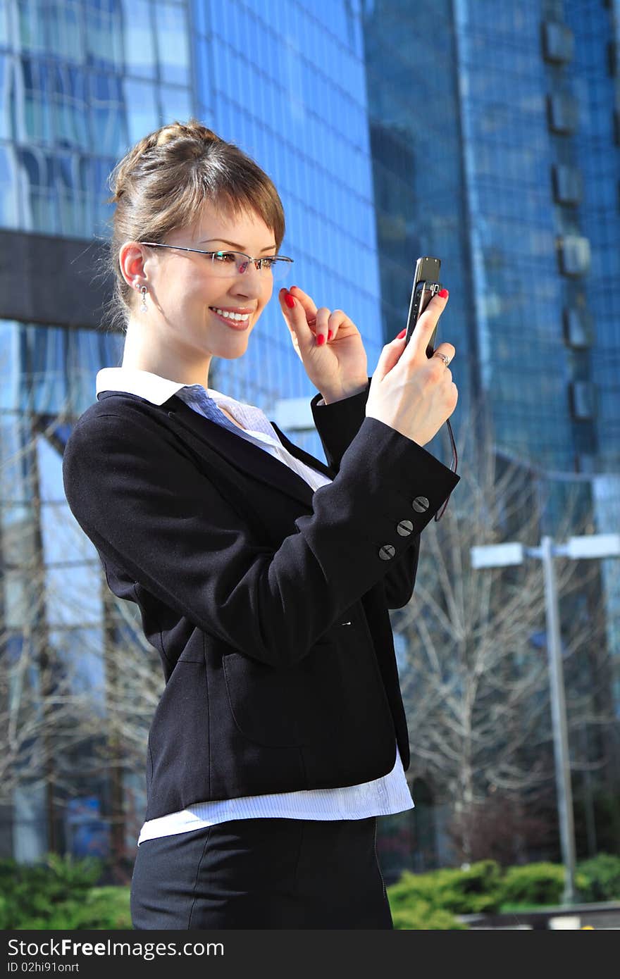 Young attractive smiling woman with a mobile cell over office building. Young attractive smiling woman with a mobile cell over office building