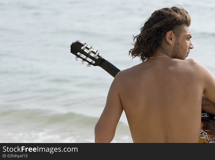 Young man playing the guitar on the beach. Young man playing the guitar on the beach