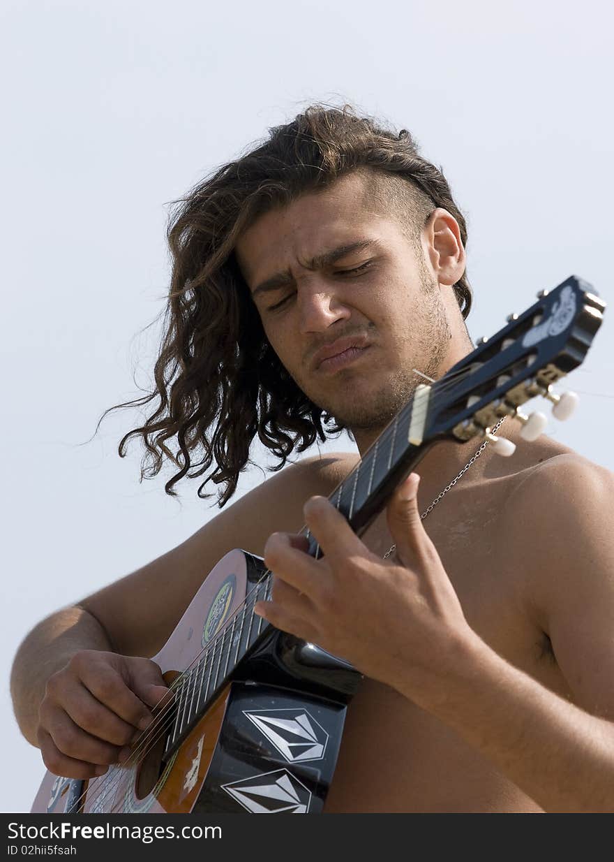 Young man playing the guitar on the beach. Young man playing the guitar on the beach