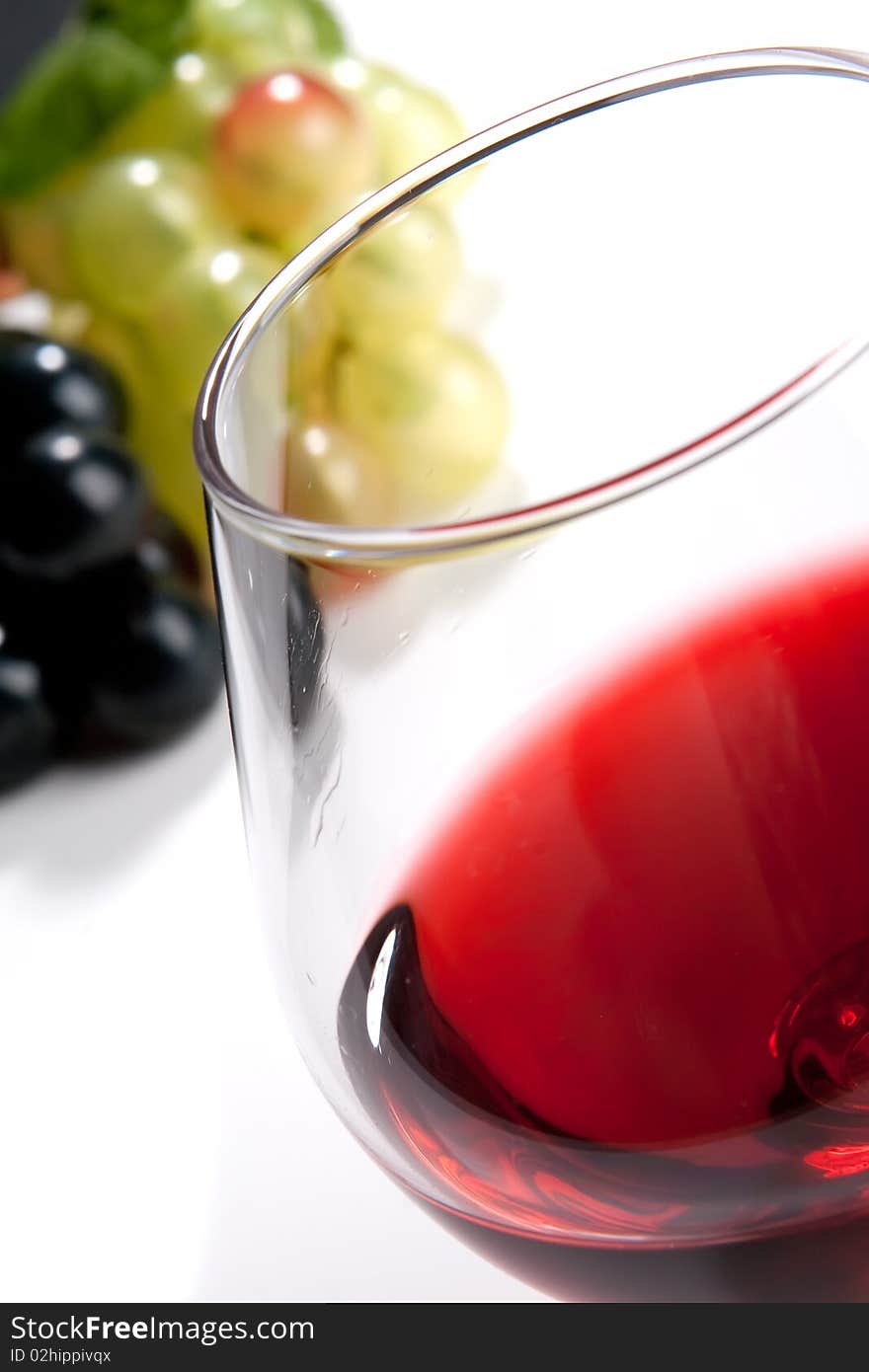 A glass of red wine and grapes on a white background. A glass of red wine and grapes on a white background