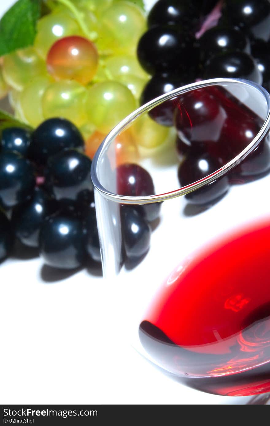 A glass of red wine and grapes on a white background. A glass of red wine and grapes on a white background