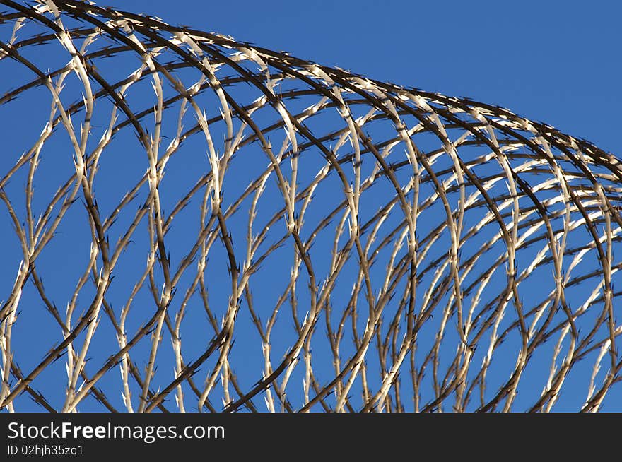Section of razor wire against blue sky.