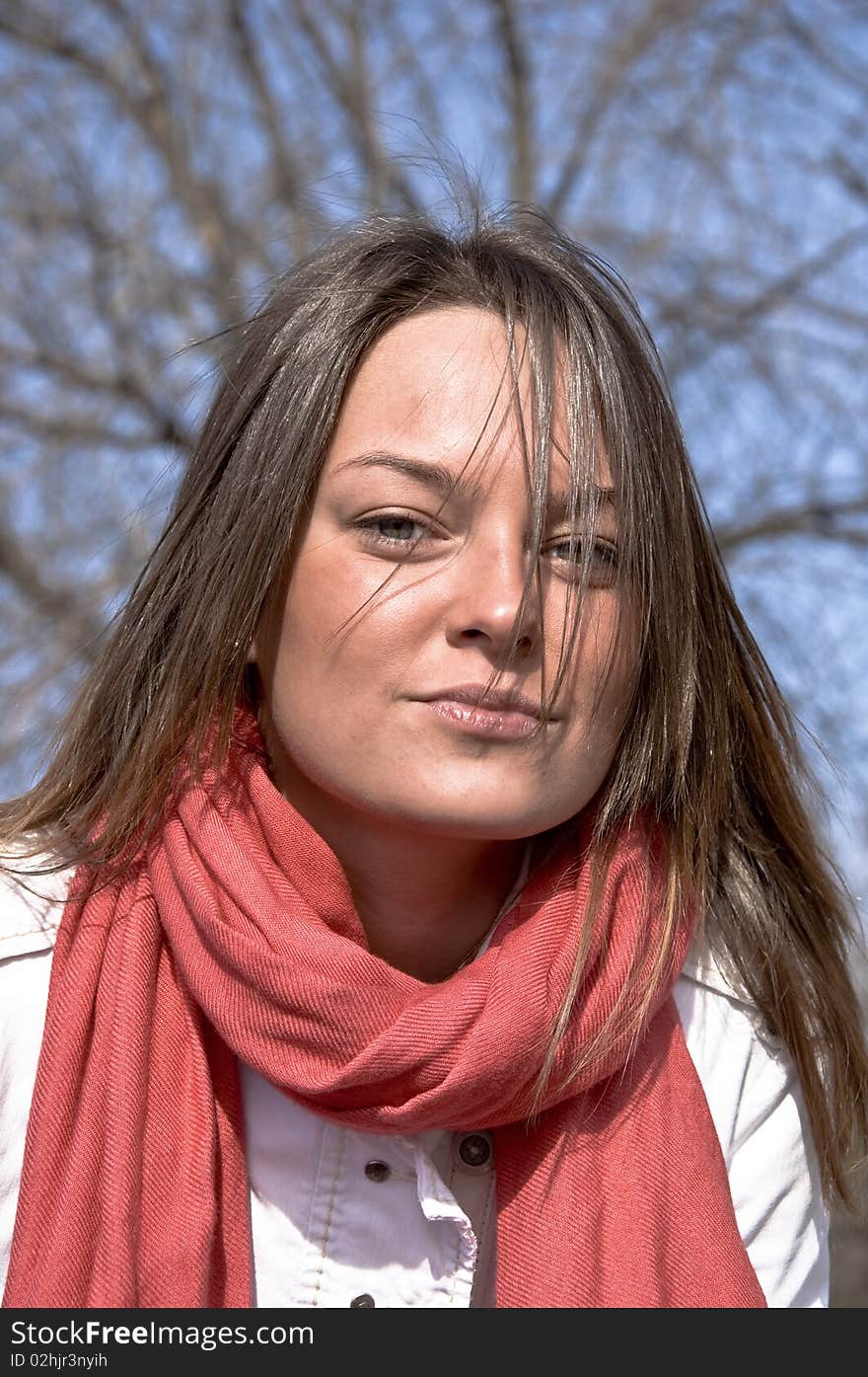 Portrait of a young beautiful girl in a red scarf. Outdoor scene. Close up.