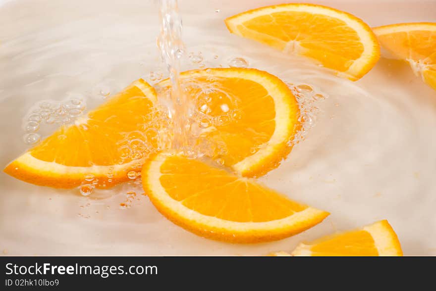 Orange slices under flowing water - concept of refreshment