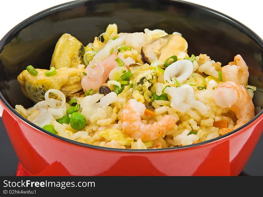 Black plate with rice and seafood on white