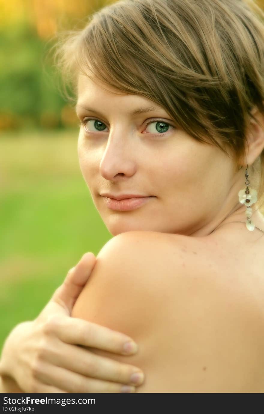 Close up of a young woman looking at you with hand lying on her shoulder. Close up of a young woman looking at you with hand lying on her shoulder