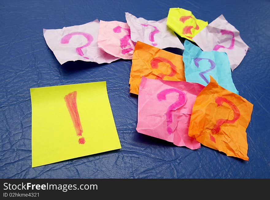 Sticker notes with exclamation and question signs over blue leather background. Sticker notes with exclamation and question signs over blue leather background