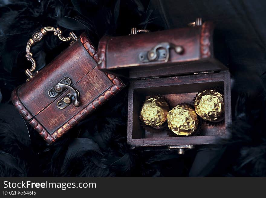 Three sweets in mini small treasure chest next to closed chest. Three sweets in mini small treasure chest next to closed chest