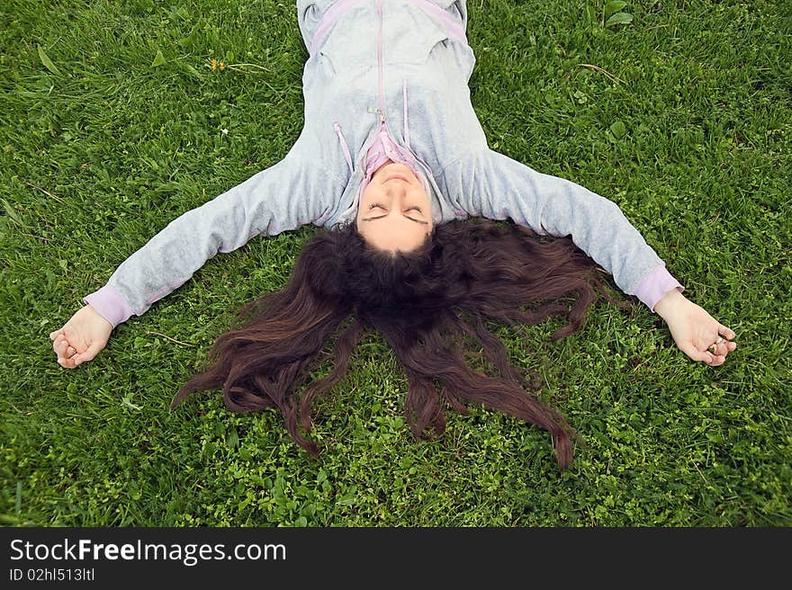 Young woman, lying on the fresh green grass, enjoying time spent outdoors. Young woman, lying on the fresh green grass, enjoying time spent outdoors