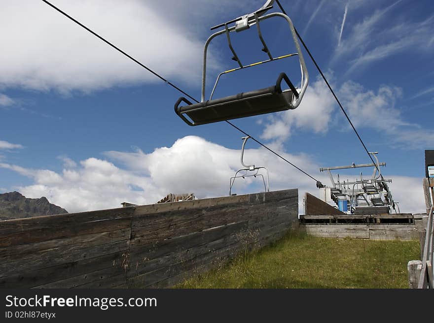 Empty chair lift at terminal stop with beautiful sky in be background.