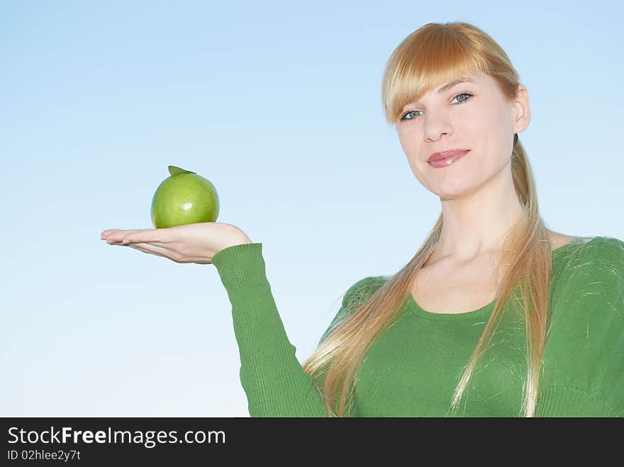 Green apple in a hand on a background of the sky. Green apple in a hand on a background of the sky