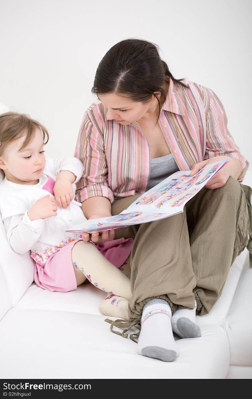 Mother and daughter reading book on sofa. Mother and daughter reading book on sofa