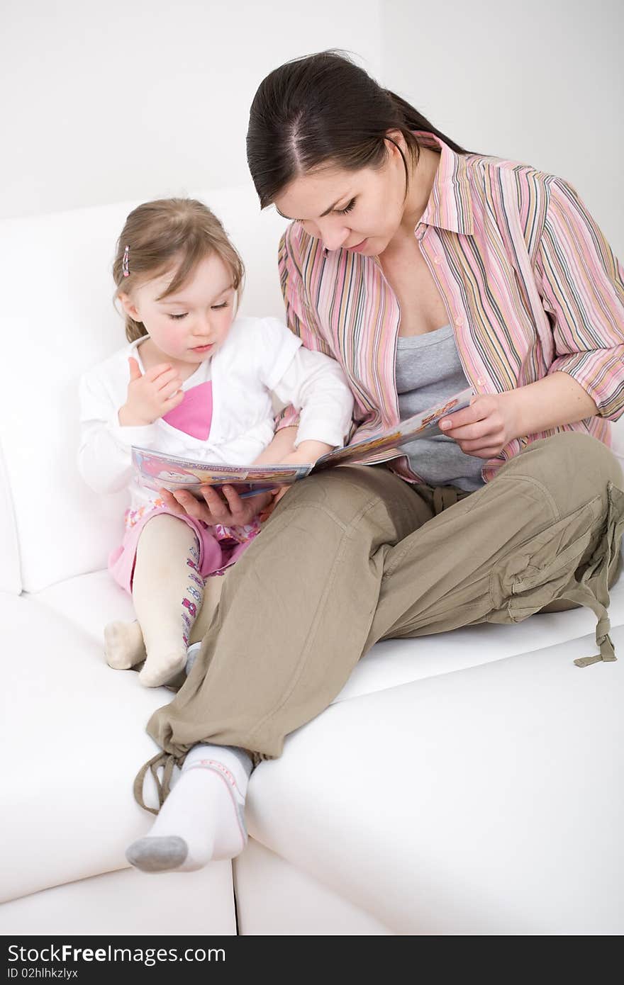 Mother and daughter reading book on sofa. Mother and daughter reading book on sofa