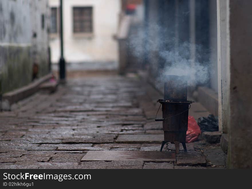 This photo is taken in an early morning in the famous Chinese riverside town Zhouzhuang. In every morning, the residents using the coal ball stove for their breakfast in the narrow street. This photo is taken in an early morning in the famous Chinese riverside town Zhouzhuang. In every morning, the residents using the coal ball stove for their breakfast in the narrow street.