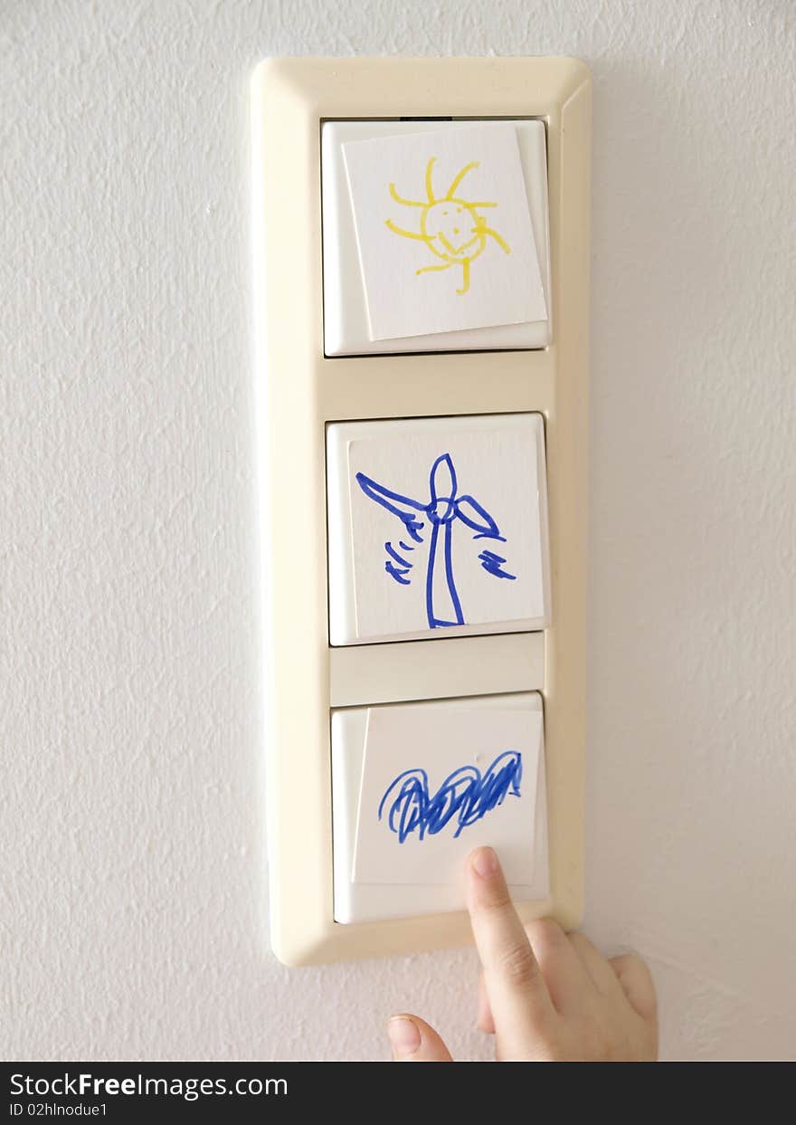 Light switch with alternative energy symbols and a child´s hand. Light switch with alternative energy symbols and a child´s hand